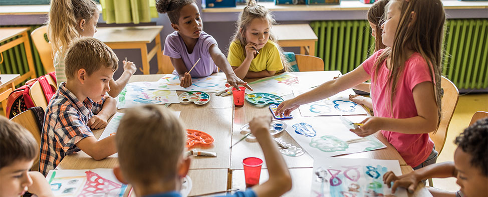 A group a young children painting at their desks.